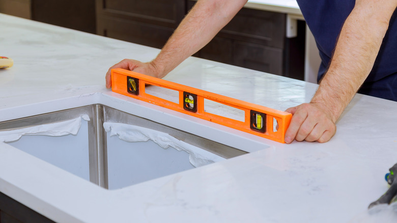 Person placing level tool on countertop during installation
