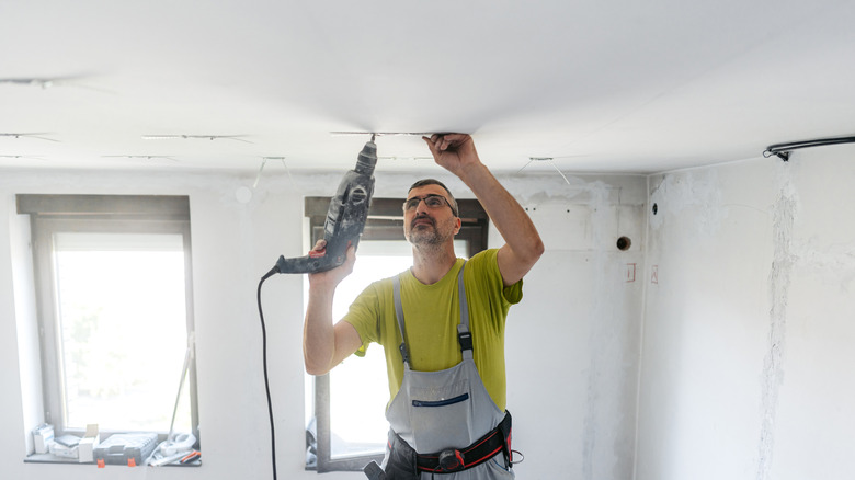 Man working on drywall in ceiling