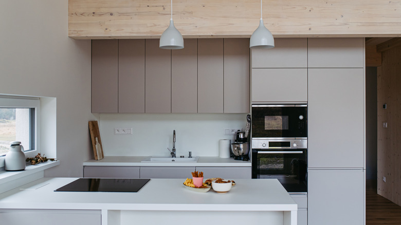 A close-up image of a minimalist kitchen in greige and white