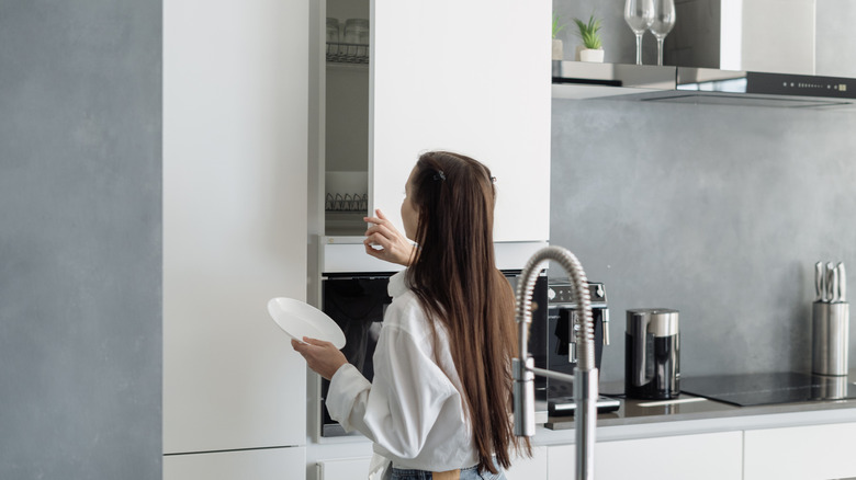 A girl opening a cabinet in a neutral miniamlist kitchen