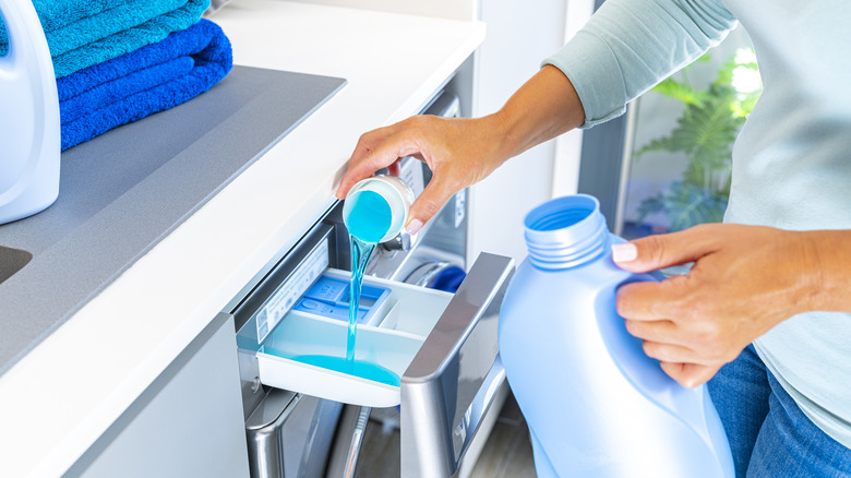Woman pours detergent into washer