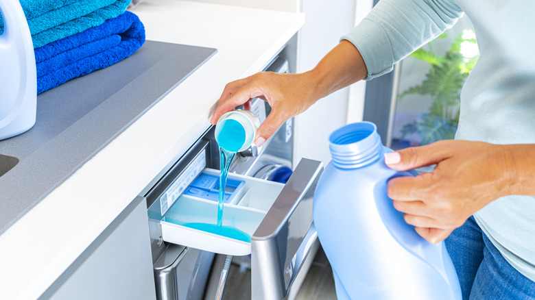 Woman pours detergent into washer