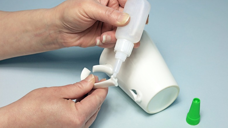 Person gluing handle onto mug