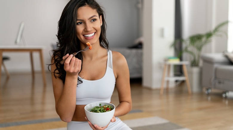 Woman eating salad home gym
