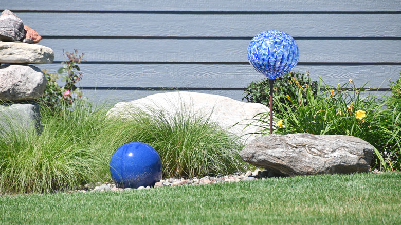 Blue orbs displayed in a garden outside a home
