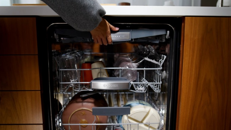 Person closing top rack on Bosch dishwasher