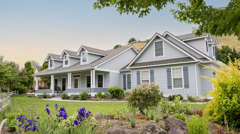 Suburban home exterior at sunset with lawn and garden visible.