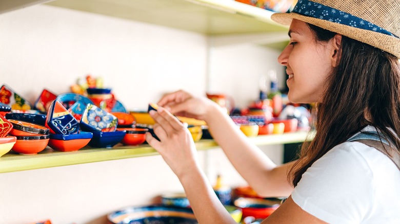 Person wearing a straw hat browsing bowls on shelf