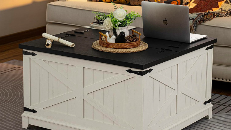 White barn-style coffee table with a laptop and other trinkets on it.