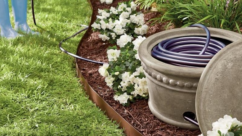 Grandin road beaded hose pot placed in garden bed with hose