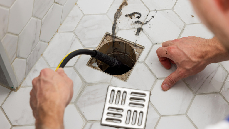 A man unblocking a floor drain
