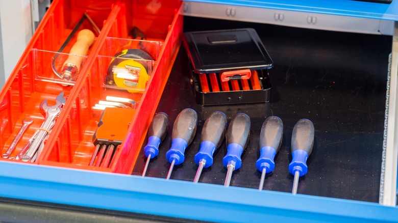Screwdrivers and other tools neatly arranged in open toolbox drawer