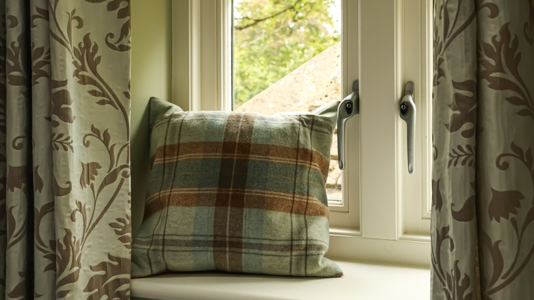 Curtains on either side of a window seat with a pillow