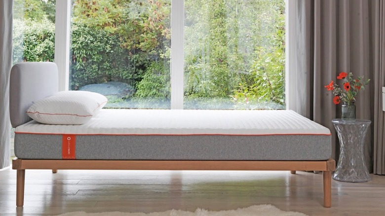 A white Dormeo mattress topper with orange trim on top of a grey mattress
