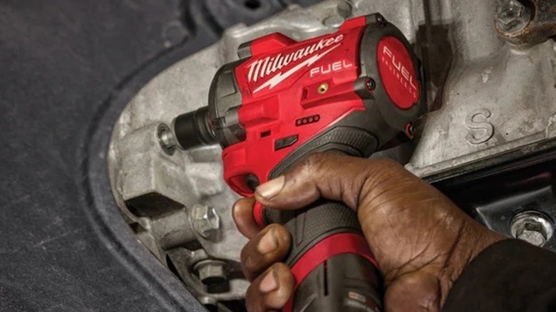 Person using a Milwaukee impact driver on bolts