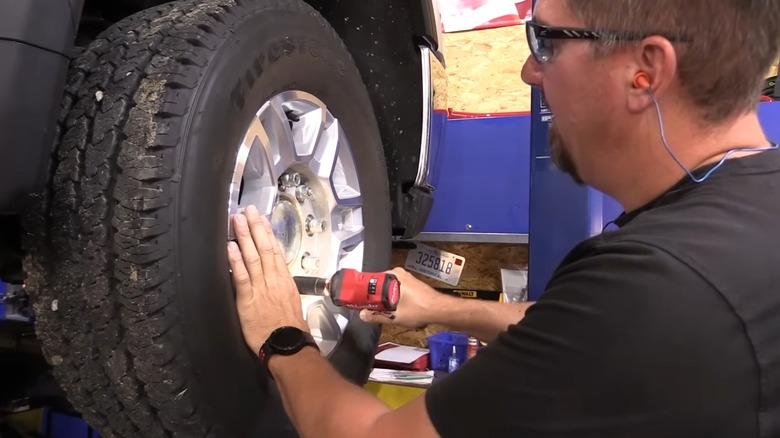Person using a Milwaukee impact driver on a tire