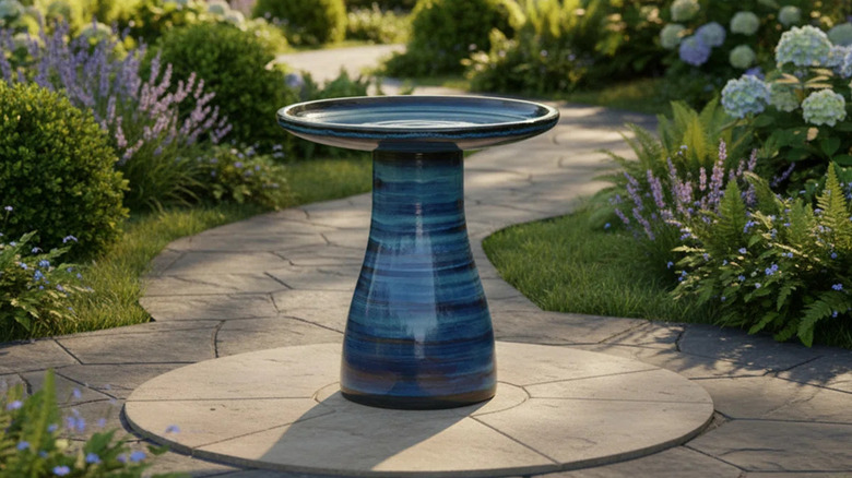 A dark blue bird bath on a garden path.