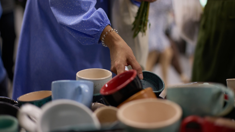 A person sorts through dishware at a thrfit store