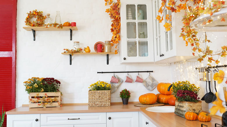 A kitchen decorated for Thanksgiving with garlands, pumpkins, and fall flowers