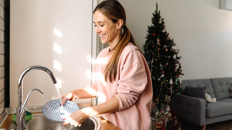 smiling woman washing dishes during holidays