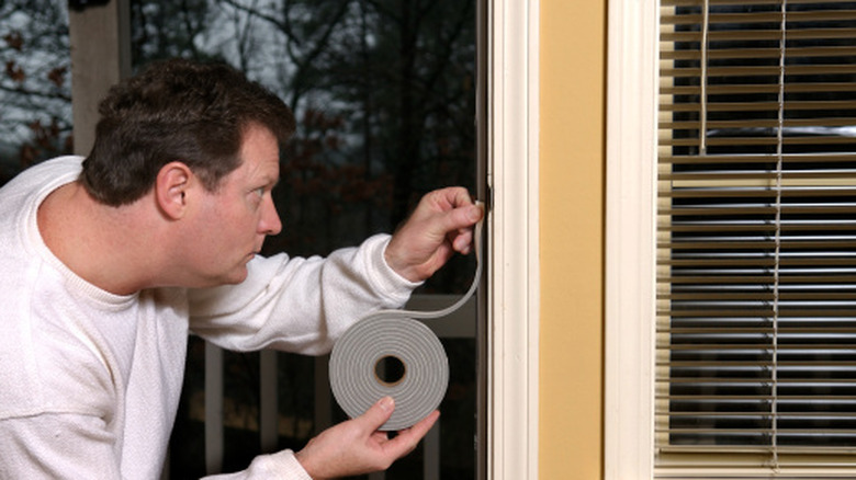 a homeowner applying weatherstripping to an entry door