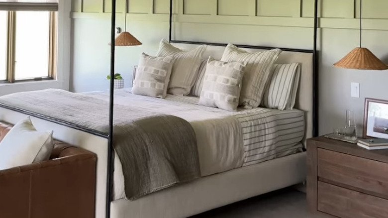 A modern canopy bed in front of a light green wall.