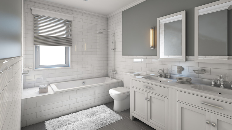 A white and gray bathroom with a built-in tub, a double vanity sink, and white subway tiles.