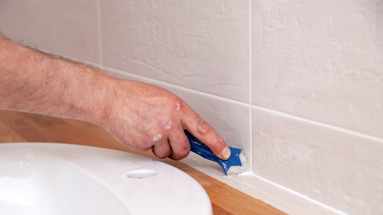 person sealing bathroom tiles