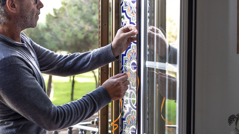 Man installing weatherstripping around window