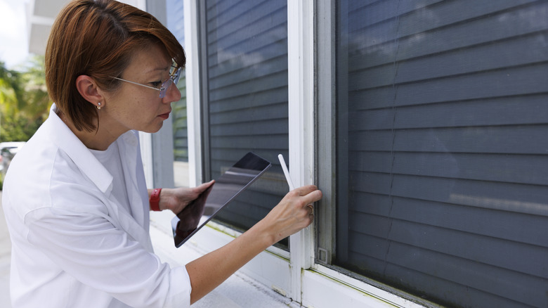 Woman inspecting seal around a window