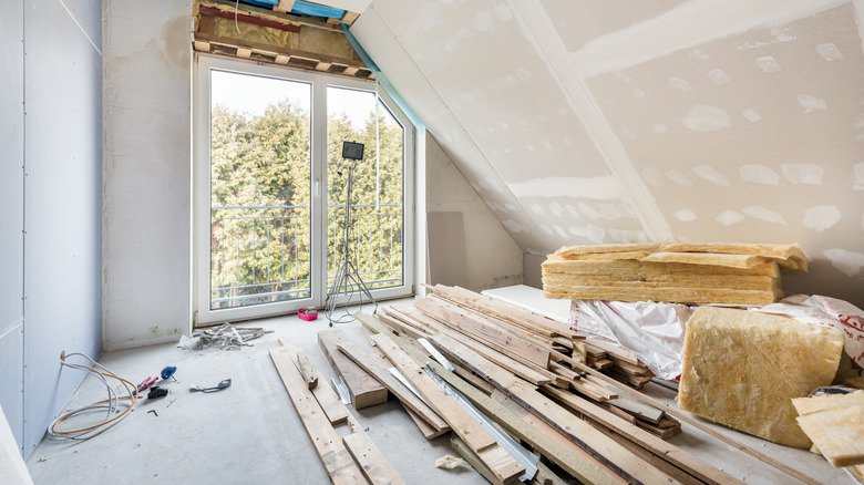 An empty room under construction with an angled ceiling and glass sliding doors