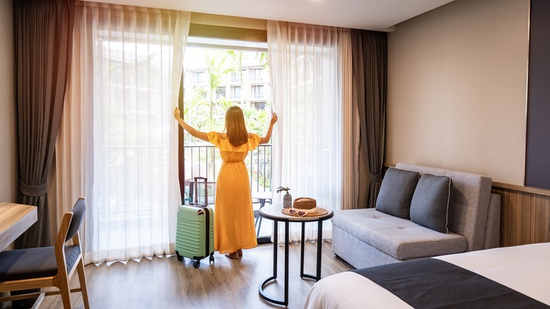 Guest opening curtains in hotel room