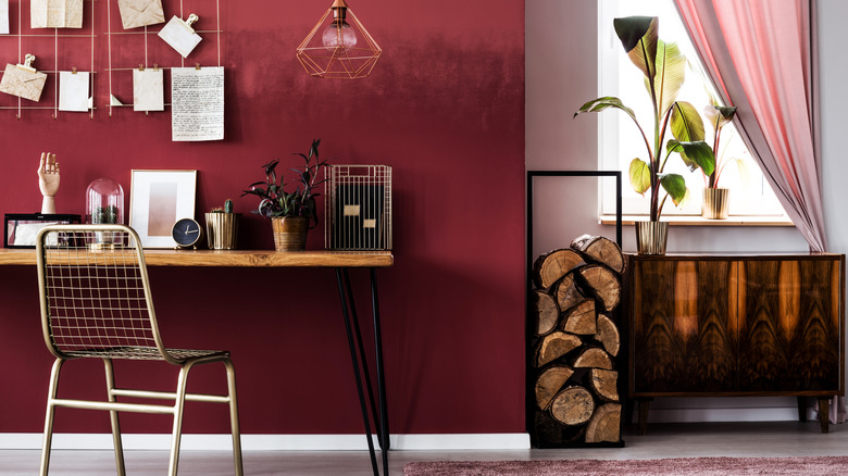 An oxblood red room with a dark wood side table and desk