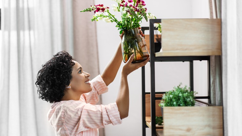 woman styling flowers on shelf