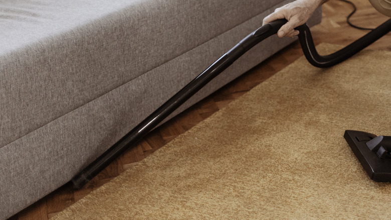 vacuuming under the sofa 