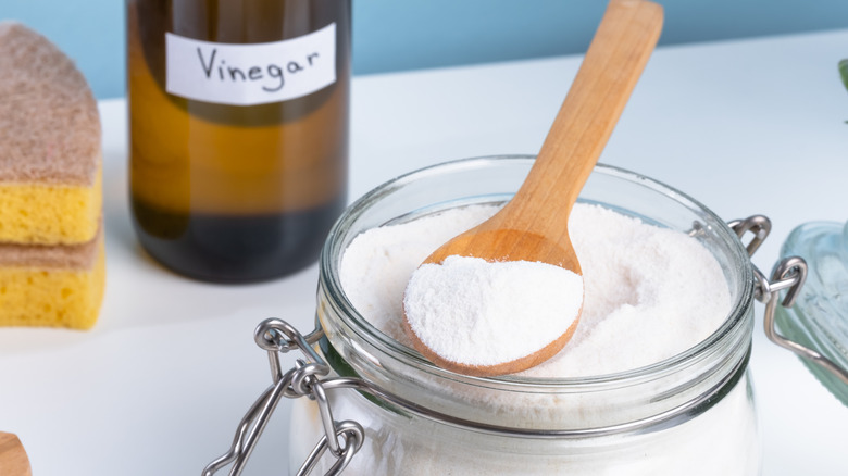 a jar of epsom salt with a bottle of vinegar in the background