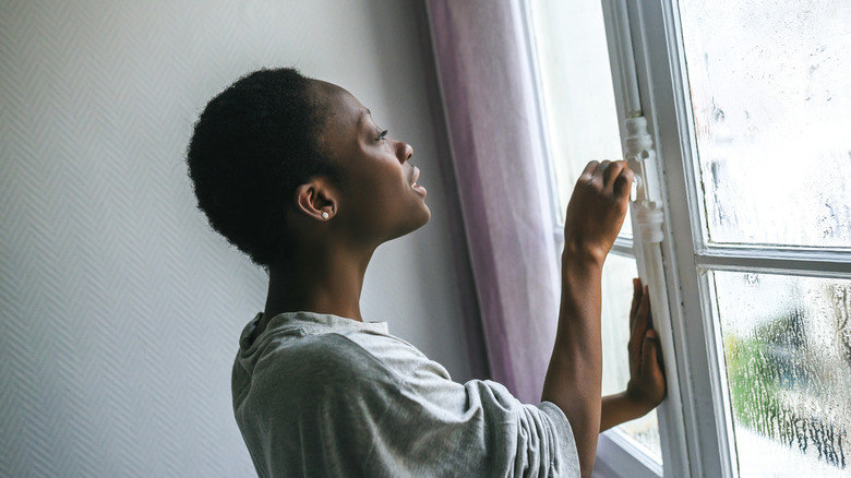 Woman opening a window in her home
