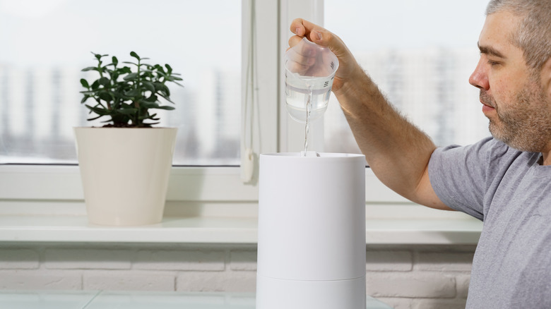 Man pouring water into a humidifier tank