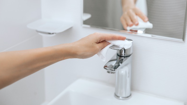 person wiping bathroom sink