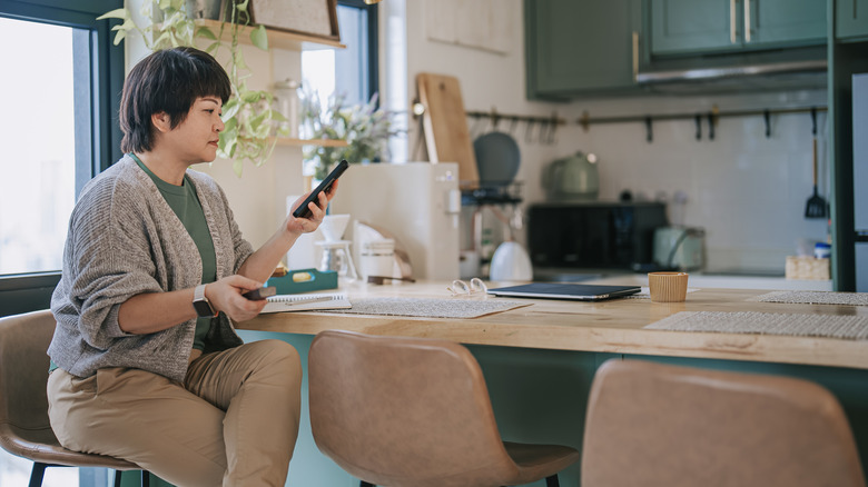 A person sits on a chair at a kitchen island.