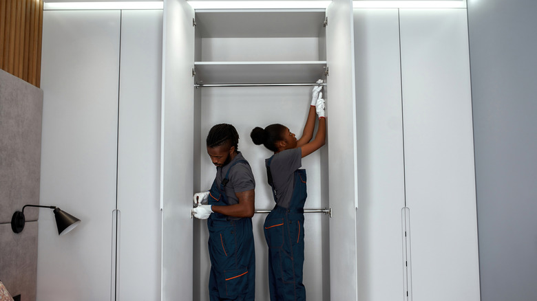 Two people attaching doors to a closet
