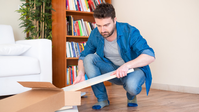 Person removing furniture pieces from a box to assemble them
