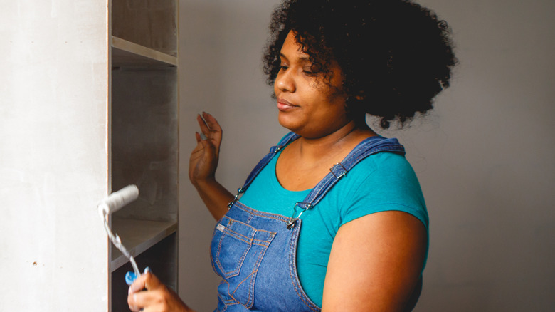 Woman painting an IKEA cabinet with roller brush