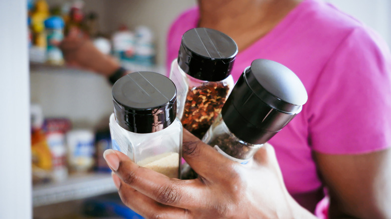 Woman retrieves bottles of spices from cabinet