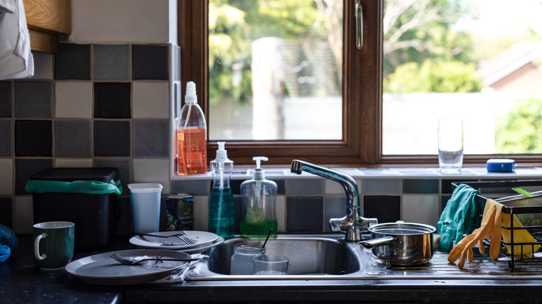 Kitchen sink with dirty plates and clutter everywhere