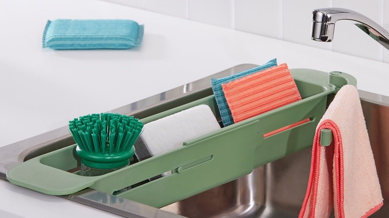 The SKOLÄST sink container in a sink stocked with kitchen essentials.