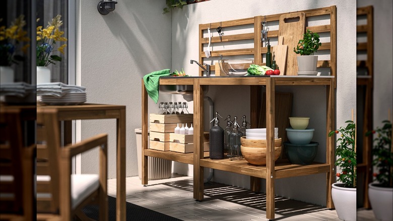 The NÄMMARÖ potting table and a side table sit on a patio with bowls and other kitchen utensils on display.