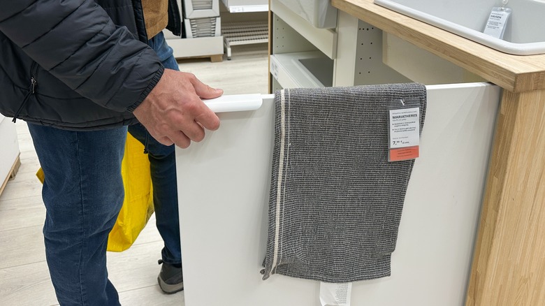 Man opens drawer to inspect gray fabric in Ikea showroom, showcasing modern storage solutions and home decor ideas