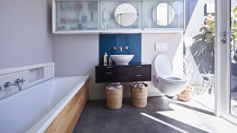 A neutral bathroom with white appliances and a blue backsplash behind the sink