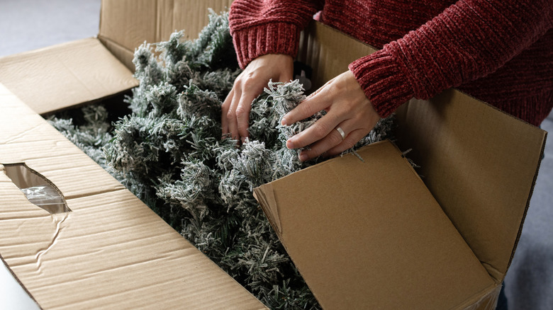 Woman unpacking an artificial Christmas tree from a storage box at home